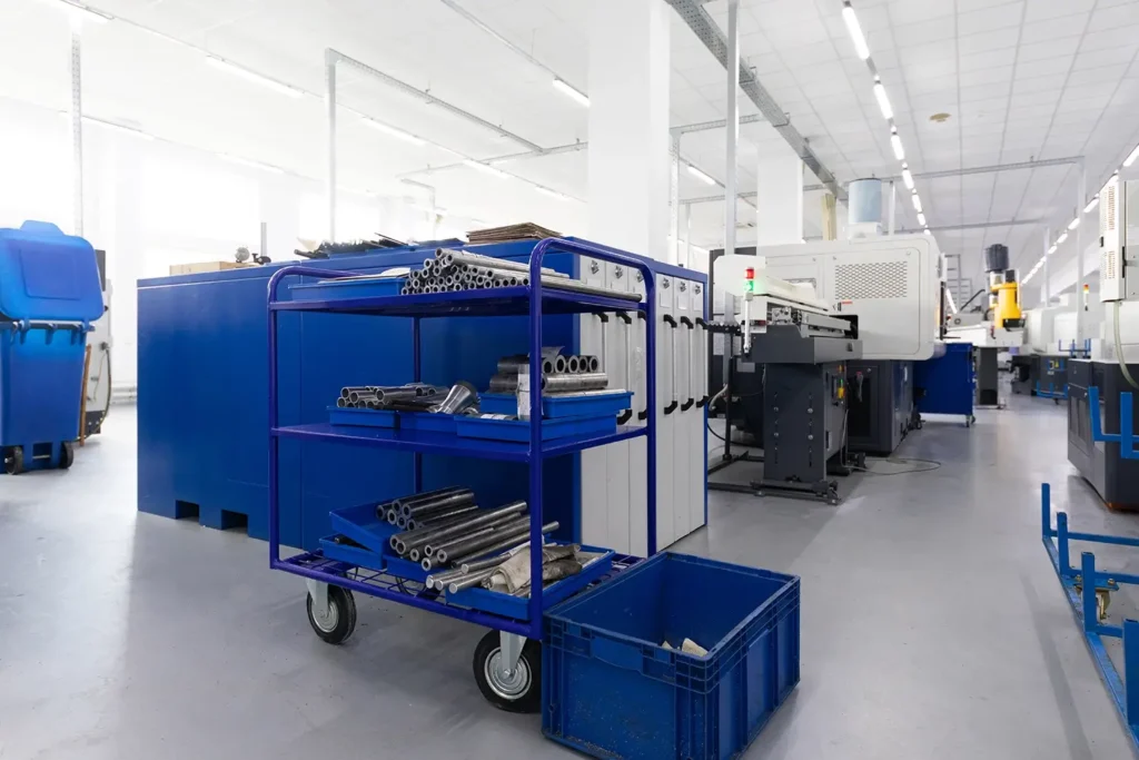 Blauer Wagen mit Metallstäben in einer hellen, modernen industriellen Fabrikumgebung.