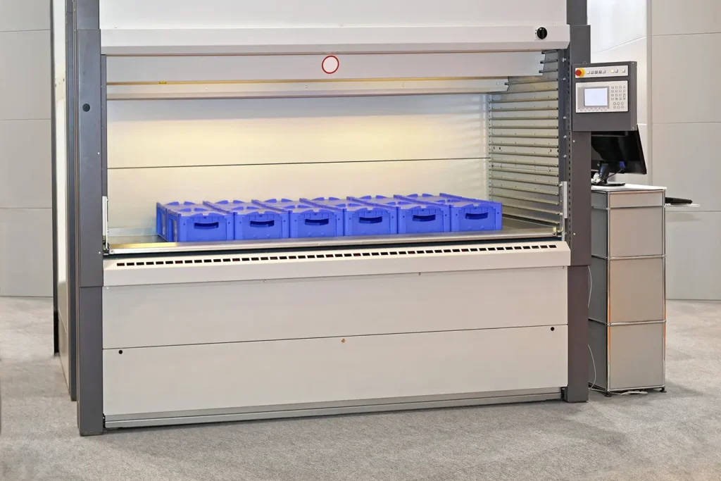 Automatisiertes Lager mit blauen Behältern und einem Computer-Bedienfeld.